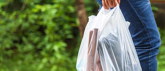 a person walking holding a plastic bag in their hand.